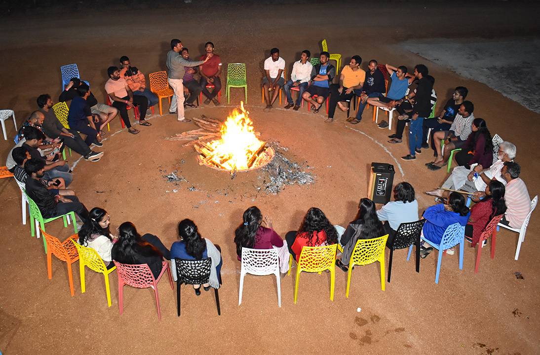 Bonfire pit at Go Ranch resort near Hyderabad, surrounded by people enjoying the warmth and ambiance